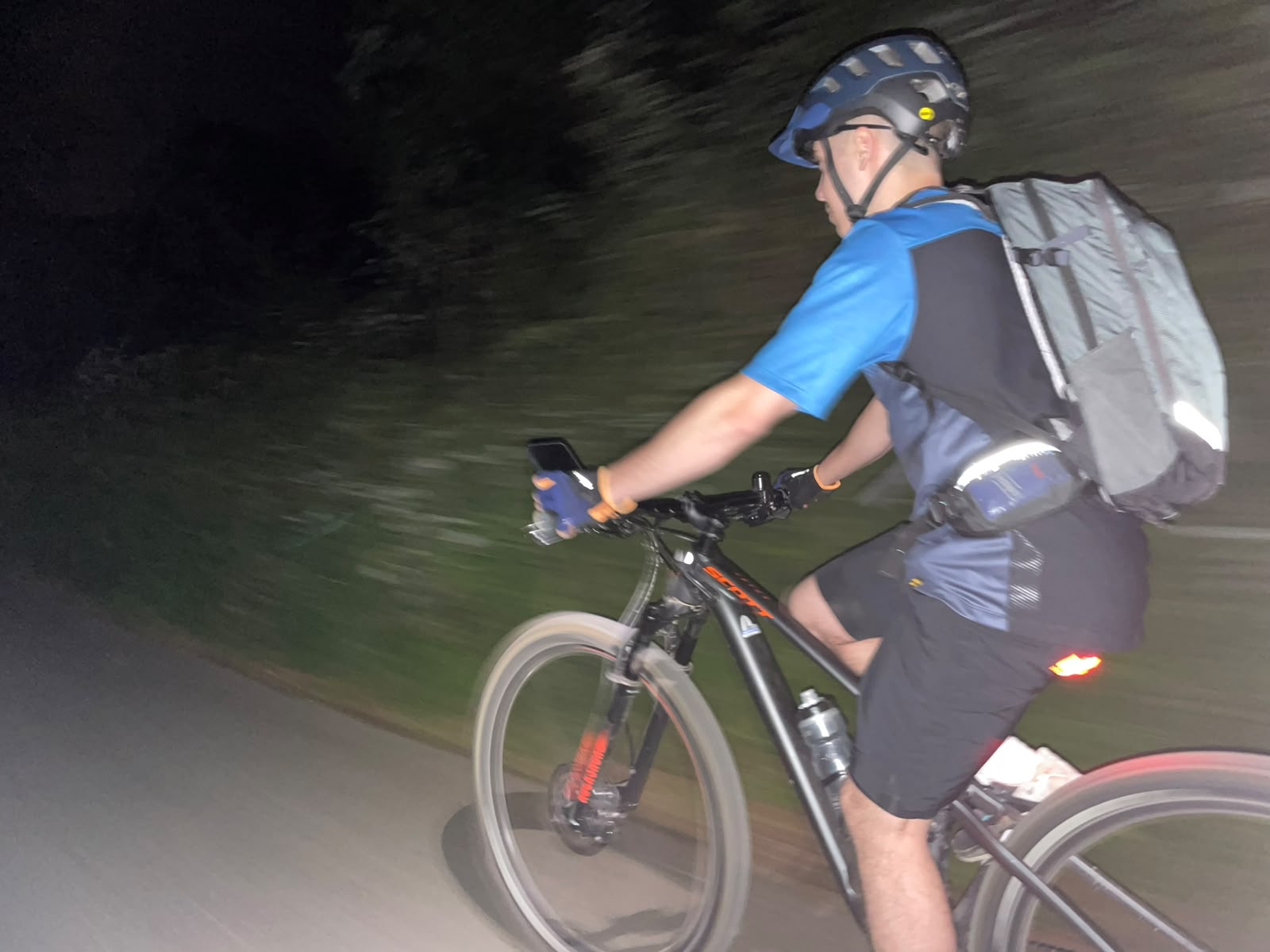 Ein Mountainbiker mit Helm und Rucksack am Abend