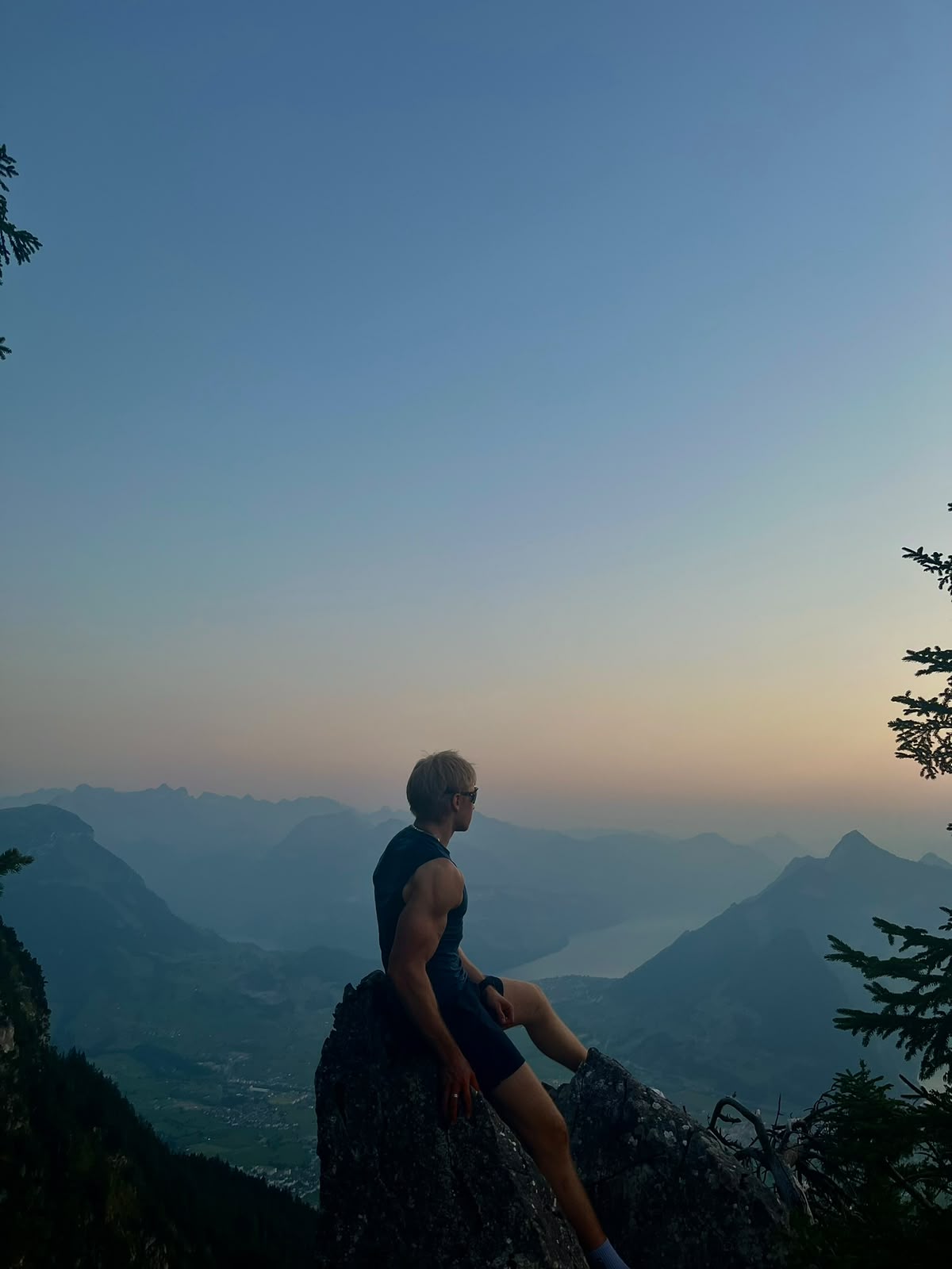 Amos sitzt auf einem Felsen mit Aussicht auf See und Berge